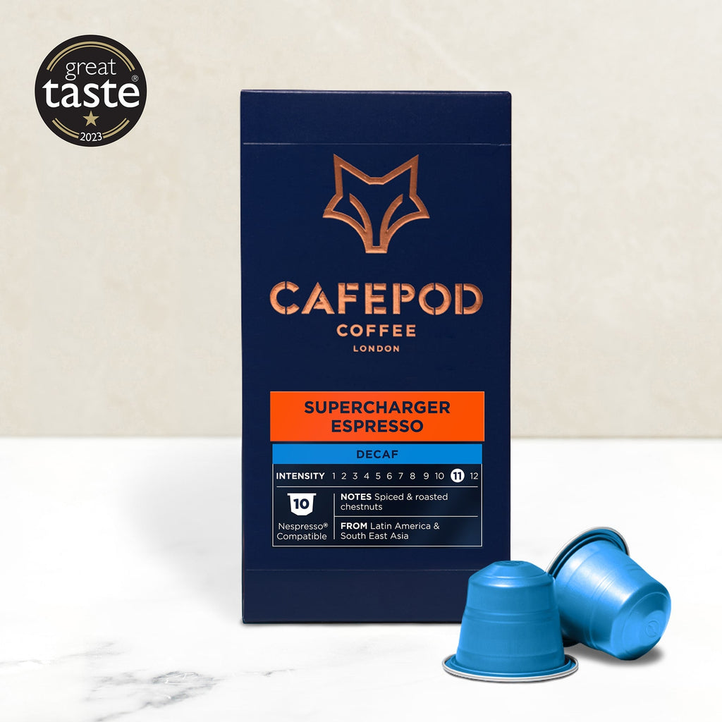 Packaging of CaféPod Coffee's Supercharger Espresso, decaf variety, with two blue coffee pods in front. The packaging is predominantly dark with orange and white text and a graphic of a fox's head.