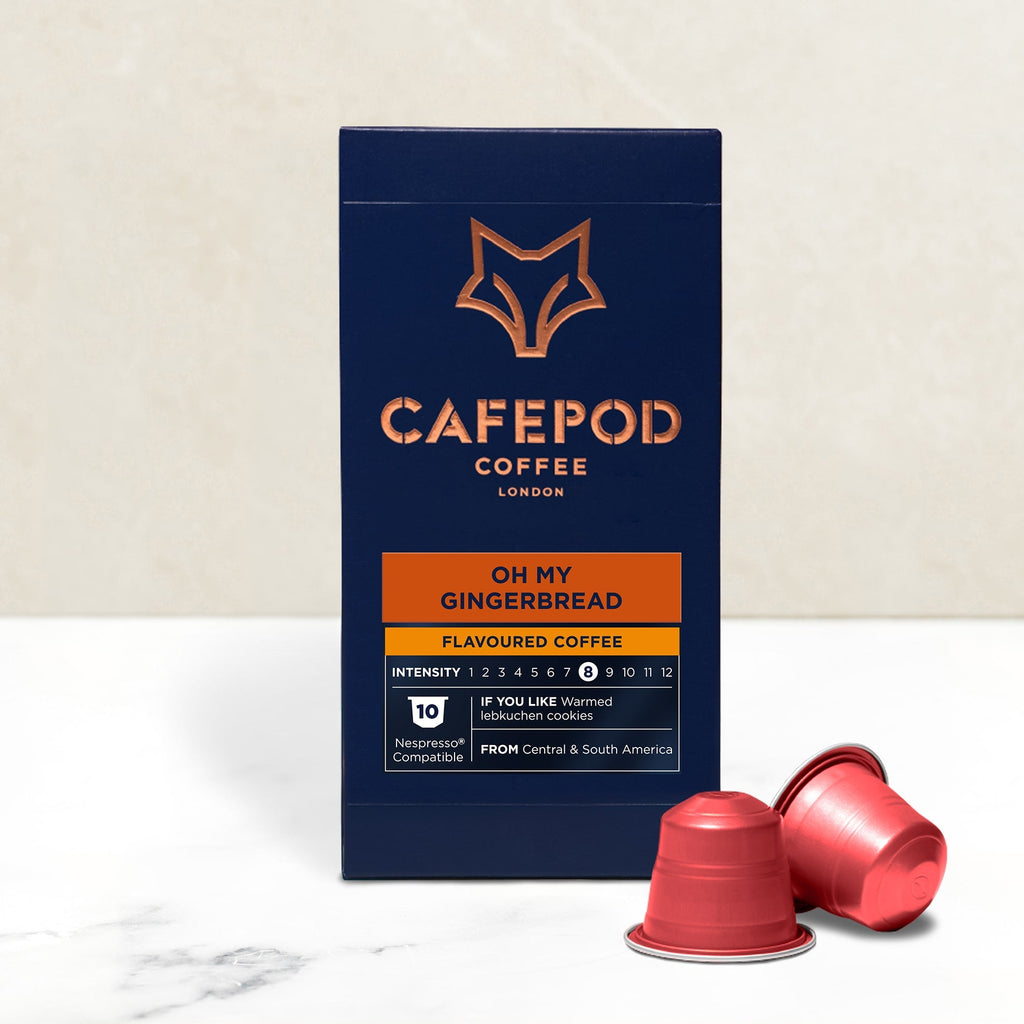 A box of CaféPod coffee capsules with the flavor 'Oh My Gingerbread' and two red capsules placed in front.