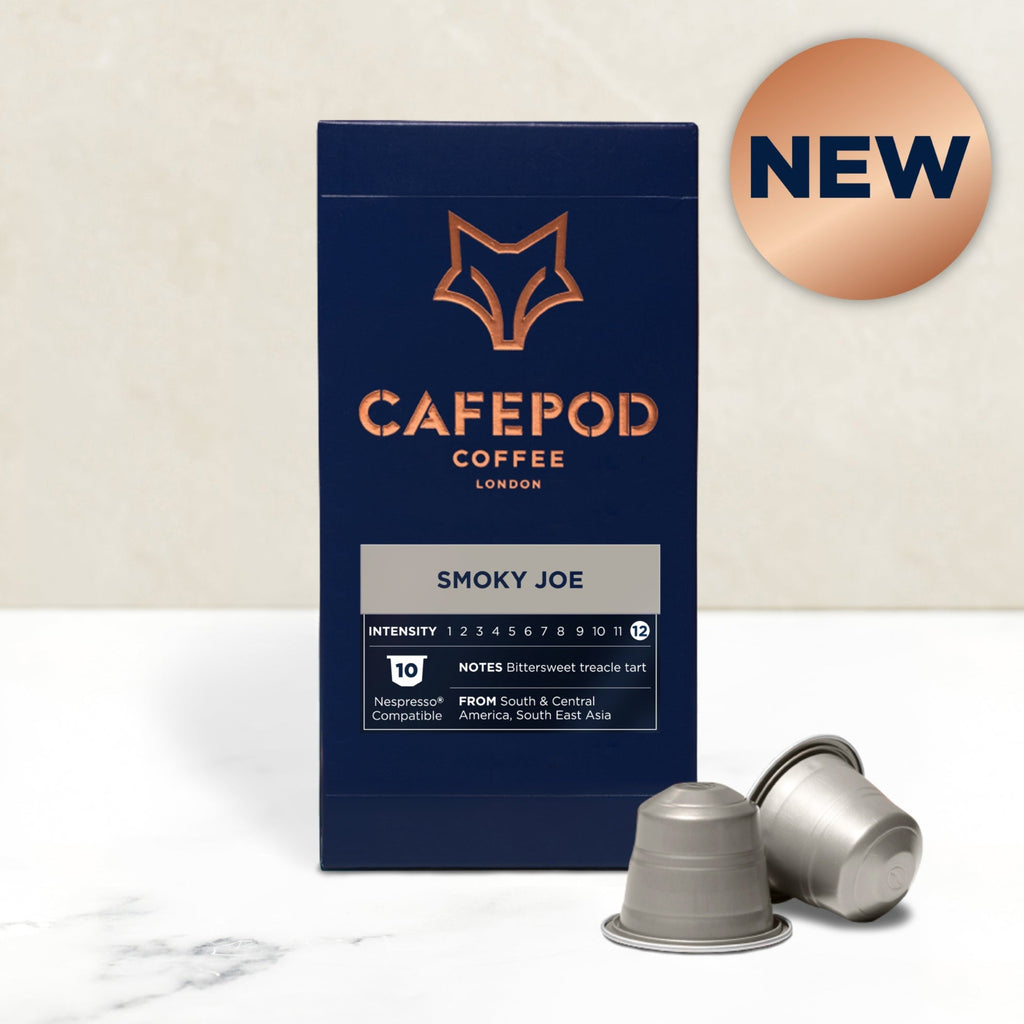 A box of Cafepod coffee capsules with the Smoky Joe variety shown. The box is dark blue with the product name and a fox logo, and there are capsules displayed in front of the box