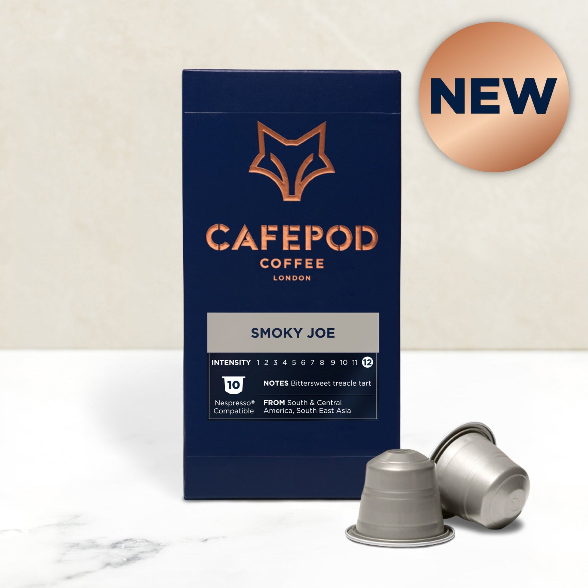 A box of Cafepod coffee capsules with the Smoky Joe variety shown. The box is dark blue with the product name and a fox logo, and there are capsules displayed in front of the box